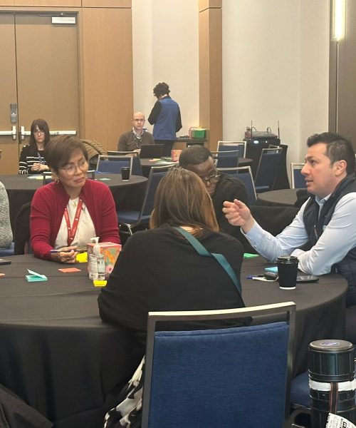 People engaged in a discussion around a table at a conference venue.